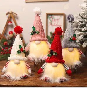 Close-up of four glowing Christmas gnomes with LED lights and knitted hats on wood