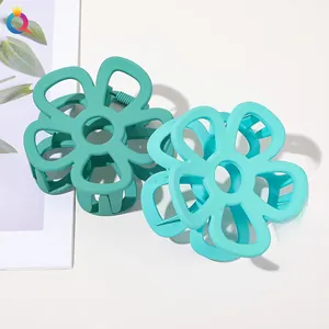 Detail view of two matte flower hair claws in forest green and light sage shades