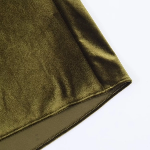 Détail de l'ourlet d'une robe en velours vert foncé montrant la double couture précise