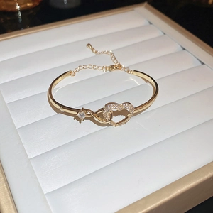 Detail view of gold hollow heart and infinity bangle with cubic zirconia and adjuster
