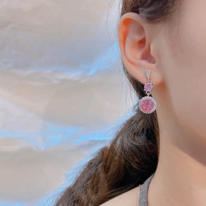 Close-up of elegant halo-set pink zircon drop earrings on model for a luxury look