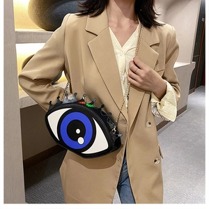 Close-up of blue eye-shaped crossbody bag with gold chain and black crown eyelashes