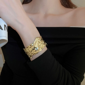 Close-up of golden irregular lava texture wide cuff bracelet with metallic finish