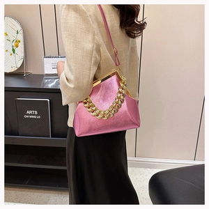 Close-up of pearl pink leather handbag with gold chain strap and metal frame clasp