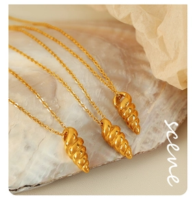 Detailed macro shot of three gold spiral conch shell pendants on pearl oyster shells