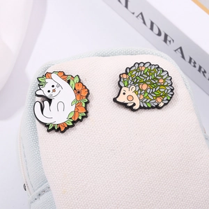 Detail of cute cat and hedgehog enamel pins attached to a canvas bag with floral accents