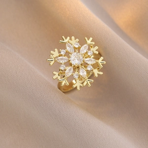 Anello dorato a fiocco di neve con zirconi su uno sfondo di tessuto beige morbido