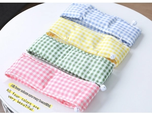 Detail of four plaid cooling scarves in pink, green, yellow, and blue with white buckles