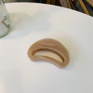 Close-up of sleek khaki resin hair claw clip with amber texture and polished finish