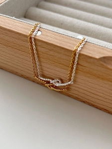 Detail of gold and silver braided heart bracelets on a wooden jewelry box edge