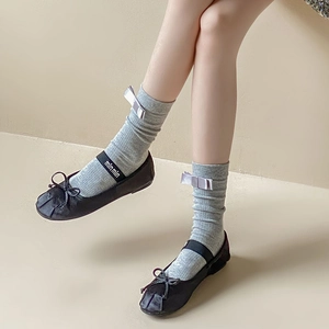 Detail of grey cotton mid-calf socks with silver bow paired with Mary Jane shoes
