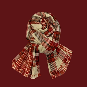 Detail of red and beige checkered knit scarf with soft tassel fringe on red background