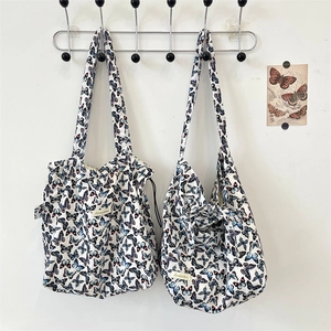 Detail of butterfly print canvas tote bag with slim shoulder straps and a small brand label