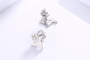 Macro shot of silver rose stud earrings with hollow petals and detailed leaf texture