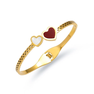 Detail of gold titanium steel bangle with red and white heart inlay and hollow patterns