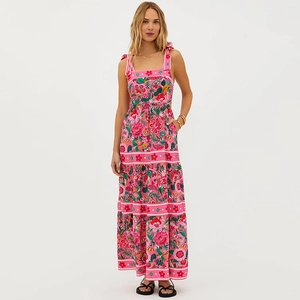 Détail d'une robe longue fleurie rose avec bretelles à nœuds et jupe bohème à volants