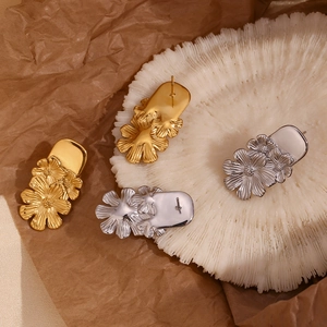 Macro view of triple daisy flower drop earrings in 18K gold and silver finishes