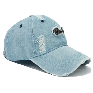 Detailaufnahme der hellblauen Jeans-Baseballkappe mit Bad-Stickerei und Used-Look-Effekten