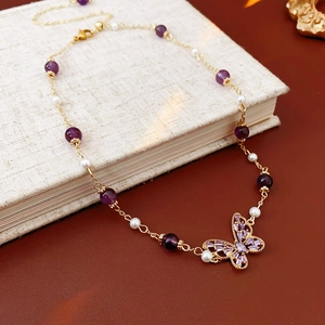 Detail of butterfly necklace with purple zircon and pearls on a vintage book surface
