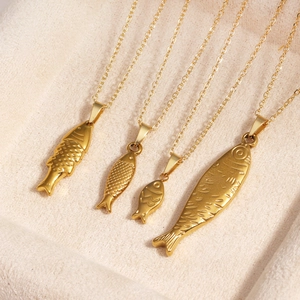 Close-up of four assorted gold tropical fish pendants on a beige velvet jewelry tray