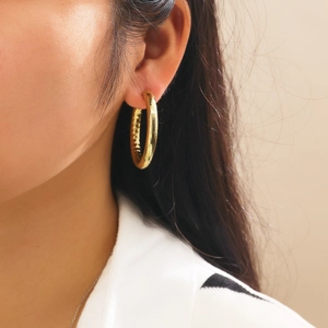 Detailed view of model wearing thick gold hoop earrings with vintage hammered metal texture