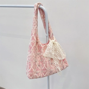 Detailed close-up of pink floral tote bag with white lace embroidery and a side bow knot