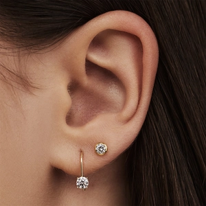 Close-up of golden S925 silver hoop earrings with clear crystals on female ear