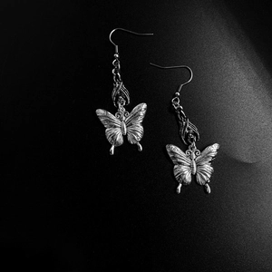 Gothic silver butterfly earrings with bat details on a textured black background