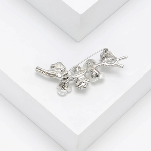 Detailed macro shot of silver branch brooch with white pearls on elegant white background