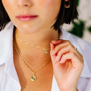 Detailed view of layered gold necklaces with square cubic zirconia and sunburst pendants