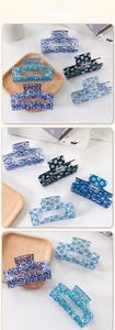 Detailed macro view of high-gloss acetate Evil Eye printed hair claws on wooden tray