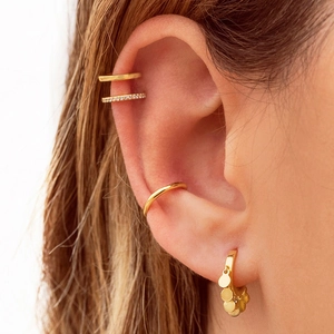 Detailed close-up of 18k gold-plated U-shaped ear cuffs and earrings with sparkling zircon