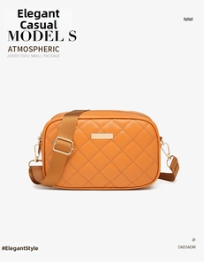 Detail of caramel quilted crossbody camera bag with wide nylon strap and gold hardware