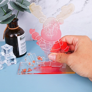 Handheld view of a festive reindeer resin craft with red gold foil and clear base
