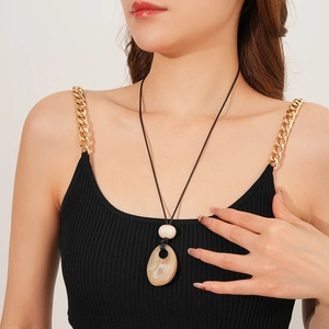 Detail of drop-shaped stone pendant with natural texture on a black cord necklace