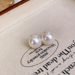 Macro detail of high-luster cherry pink pearl earrings with elegant gold pin settings