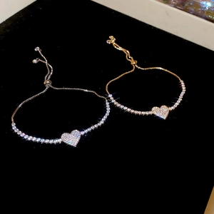 Macro detail of sparkling zircon heart charms on gold and silver tennis bracelets