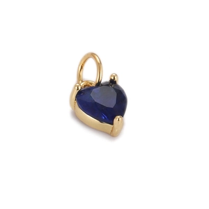 Macro detail of gold plated heart pendant with faceted navy blue zircon stone