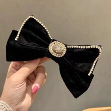 Detail of a black velvet lace bow hair clip with sparkling rhinestones and crystal center