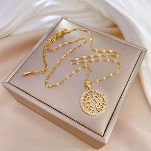 Luxurious gold coin circle necklace with micro-paved crystals on a satin jewelry box