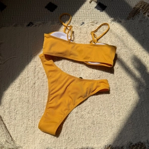 Flat lay of yellow ribbed bikini set with adjustable straps on a soft plush rug background