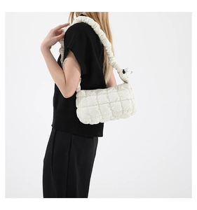 Detail of white quilted cloud bag with pleated shoulder strap on a model with high contrast