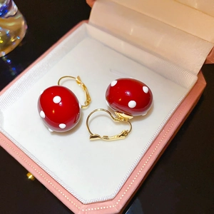 Close-up of mushroom style earring with red enamel and white polka dots in a pink jewelry box