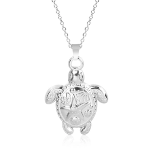 Detailed close-up of a stainless steel sea turtle pendant with embossed floral patterns