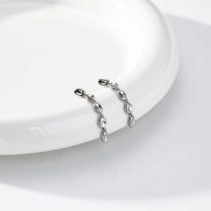 Macro shot of silver asymmetric water drop tassel earrings on white ceramic plate