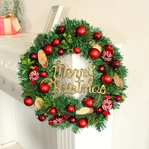 Weihnachtskranz mit roten Kugeln, Zuckerstangen und Merry Christmas Schild am Kamin