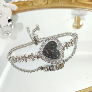 Macro shot of silver heart-shaped watch with black dial and adjustable floral link chain
