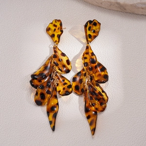 Detail of tortoiseshell acrylic petal tassel earrings with dark spots on stone background