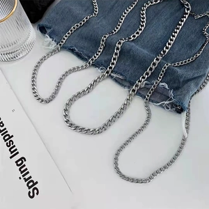 Close-up of interlocking silver stainless steel NK chains on a stylish denim background