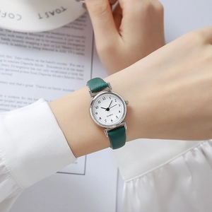 Detail of green leather strap quartz watch on female wrist with elegant white dial